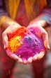 Hands full of Holi powders with festive crowd