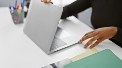 Canvas Print - African american woman closing laptop in a modern office, indicating end of work day