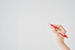 赤いボールペンを持つ女性の手と白い背景
