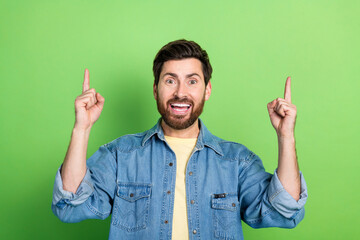 Poster - Photo of cheerful positive guy dressed jeans shirt showing up two fingers empty space isolated green color background