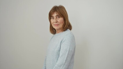 Wall Mural - Confident middle age woman with a natural smile, wearing a sweater and standing in a relaxed profile pose. she's looking to the side, enhancing her beauty against an isolated white background.