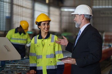 A woman worker in a yellow safety vest is talking to a foreman in a suit