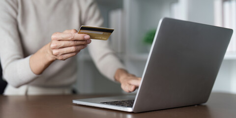 A woman is using a laptop to pay for something with a credit card