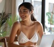 © Surachetsh - A Japanese woman, adorned in a white swimsuit, beams while engrossed in her laptop work at her workstation, displaying commitment and effectiveness in her job duties.
