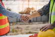 construction worker and contractor. Client shaking hands with team builder in the factory construction site.