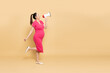 Portrait of Happy Asian pregnant woman standing and holding megaphone isolated on brown background, Speaker and announce concept, Full body composition
