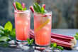 Refreshing rhubarb cocktails with basil garnish on a wet slate surface, perfect for spring celebrations or summer refreshments