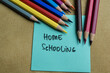 Concept of Home Schooling write on sticky notes isolated on Wooden Table.