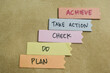 Concept of Achieve Take Action Check Do Plan write on sticky notes isolated on Wooden Table.