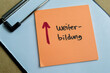 Concept of Weiter Bildung write on sticky notes isolated on Wooden Table.