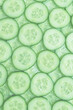 Fresh green slices of cucumber as background.