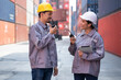Portrait Asia logistic engineer woman worker or foreman use tablet computer and walkie talkie working with engineer man at container site	