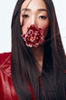 Beautiful woman in red jacket holding flower, her long hair blowing in the wind
