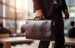 © Oleksiy - hands of businessman holding a briefcase on blurred office backg