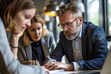 Poster - A man and two women engaged in a business meeting, looking at a laptop screen, A business man consulting with his team in a modern office