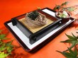 Soba noodles and seaweed on a tray, served with dipping sauce and greens