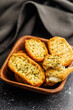 Garlic crisp bread Slices Topped With Herbs in bowl on black table.