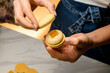 Woman in jeans with manicure makes macaron with cream filling