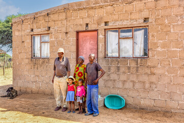 african village, large family standing in front of the house, block bricks