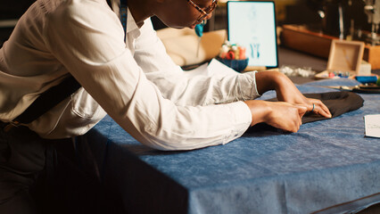 Wall Mural - Seamstress preparing fabric on table, measuring material for right fit, custom made clothes. Couturier designing new fashion collection for luxury customers in atelier workshop. Handheld shot.