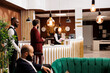 © DC Studio - Hotel staff providing luxury services for businessman travelling to attend executive conference, reception lobby. Traveling for work, entrepreneur doing check in at front desk.