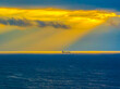 Sunrise Seascape with sunrays in the cloud covered sky and ship on the horizon