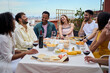 © CarlosBarquero - Group of laughing young people enjoying lunch together outdoor. Gathering of cheerful friends celebrating meal party on terrace. Concept of millennial friendship and having fun on weekend