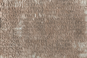 Vintage text background. Close-up of an ancient Greek stone inscription with weathered characters (Text of Roman Imperial law in ancient Greek language).