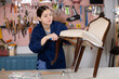 Young female carpenter working on making vintage chair in workshop
