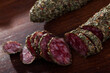 Traditional Catalan thin dry cured pork sausage Fuet with herbs sliced on wooden surface