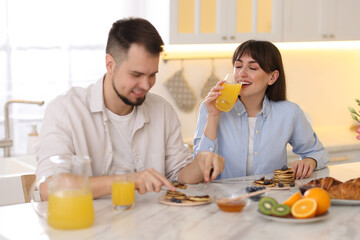 Wall Mural - Happy couple having tasty breakfast at home