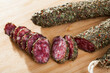Fuet, traditional spanish dry cured sausage with fine herbs on wooden table