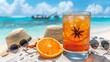 Refreshing summer drink on a sunny beach with orange slice and star anise, hat, sunglasses, and turquoise sea in the background