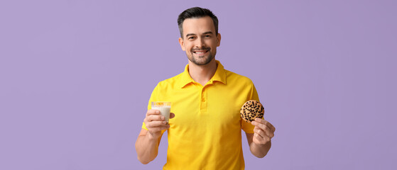 Poster - Handsome man with tasty cookie and glass of milk on lilac background