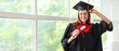 Female graduate student with diploma near window in room