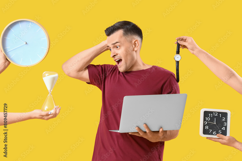 Stressed young man and hands with clocks on yellow background. Deadline concept