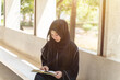 A beautiful Muslim students are intently reading Quran in the school building during breaks time in university with sun fare and blurred background.
