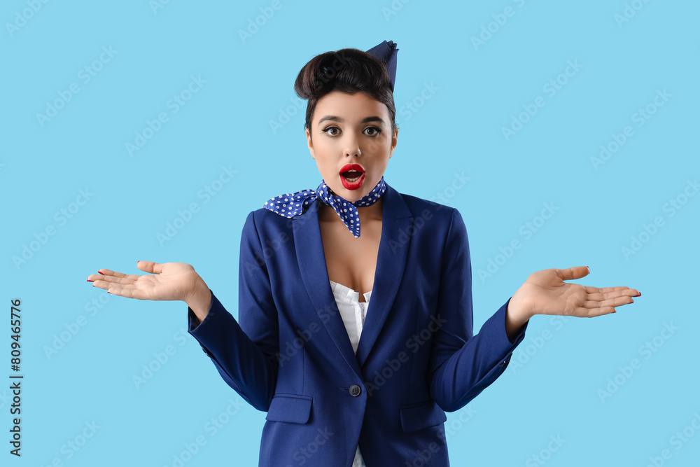 Shocked young pin-up stewardess on blue background