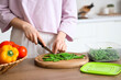 © Pixel-Shot - Woman cutting green beans for freezing on wooden table in kitchen