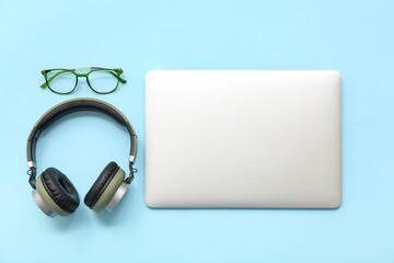Wall Mural - Modern laptop, headphones and eyeglasses on color background