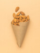 A package of kraft paper with almonds on a beige background.
