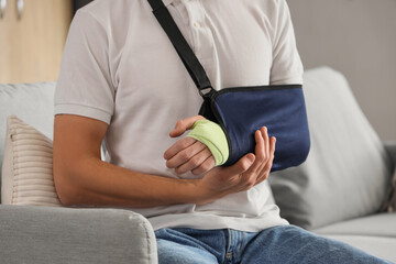 Wall Mural - Injured young man after accident sitting on sofa at home, closeup