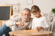 © Pixel-Shot - Grandfather and his cute little grandson playing chess at home
