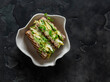 Delicious breakfast, brunch, snack - wholegrain sandwich with avocado, scrambled eggs and microgreens on a dark background, top view