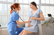 © Pixel-Shot - Female doctor examining pregnant woman with stethoscope in clinic