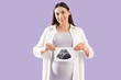 © Pixel-Shot - Young pregnant woman with sonogram image on lilac background