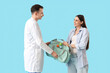 © Pixel-Shot - Young pregnant woman taking maternal bag from doctor on blue background