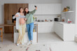 © Pixel-Shot - Young pregnant lesbian couple taking selfie in kitchen