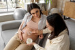 © Pixel-Shot - Young pregnant woman with wife applying cream on her belly at home