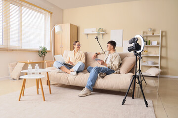 Wall Mural - Podcaster and guest with gadgets on sofa talking in studio